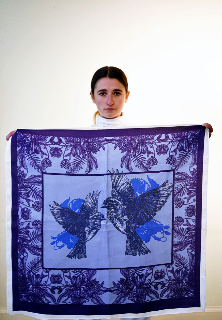 Louisa holding a purple and blue silk scarf printed with two sparrows